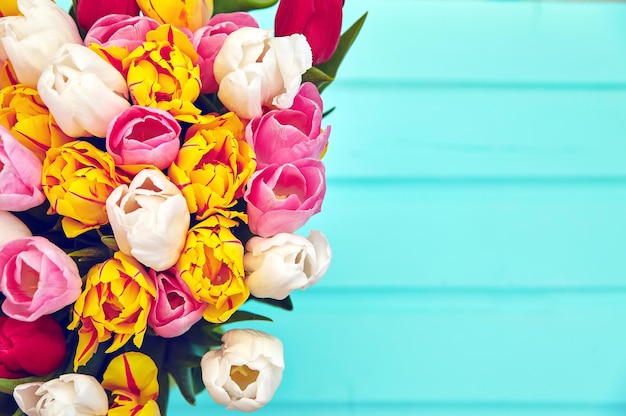 Bouquet of fresh multicolor tulip flowers on old blue wooden table