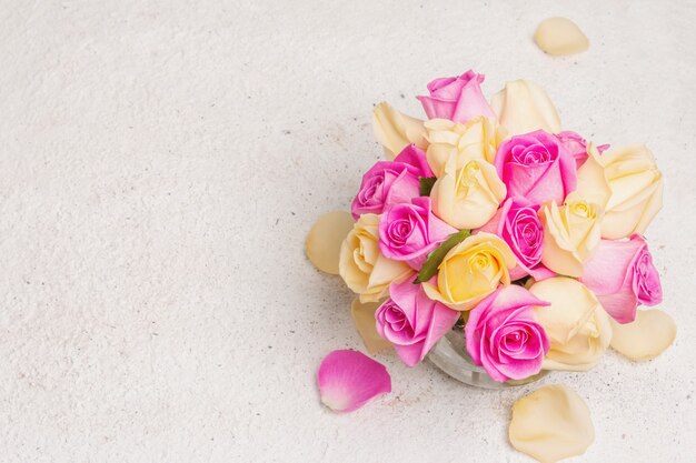 Bouquet di rose multicolori fresche in un vaso. il concetto festivo per matrimoni, compleanni, 8 marzo, festa della mamma o san valentino. biglietto di auguri, sfondo chiaro