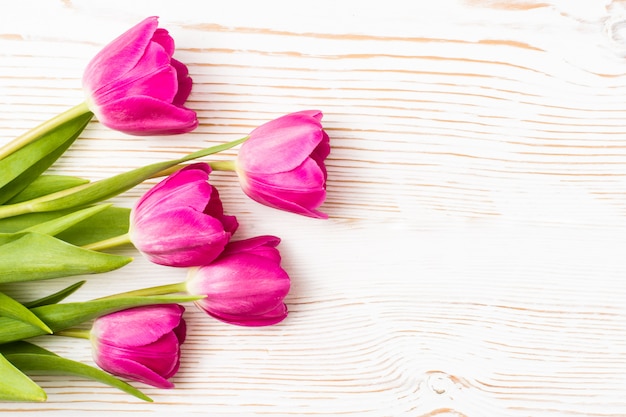 Bouquet of fresh pink tulips on a white wood, top view