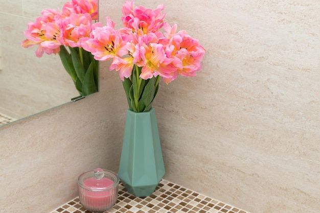 Bouquet of fresh tulips on bathroom countertop with tile backsplash