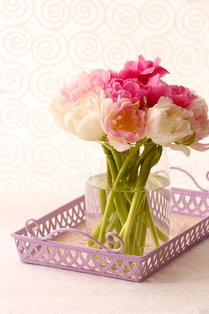 Bouquet of fresh tulips in wicker tray on light background