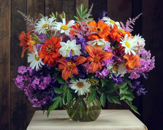 Bouquet of garden flowers in a glass jug. 