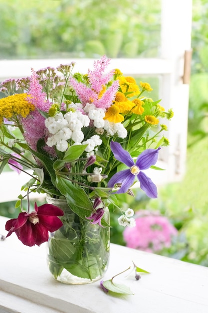 Bouquet of garden flowers on window sill