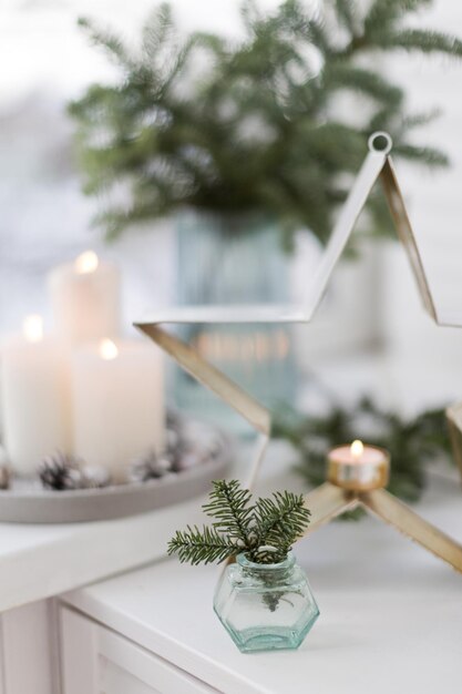 Bouquet of green spruce branches in vase white burning candles and star decoration at home interior