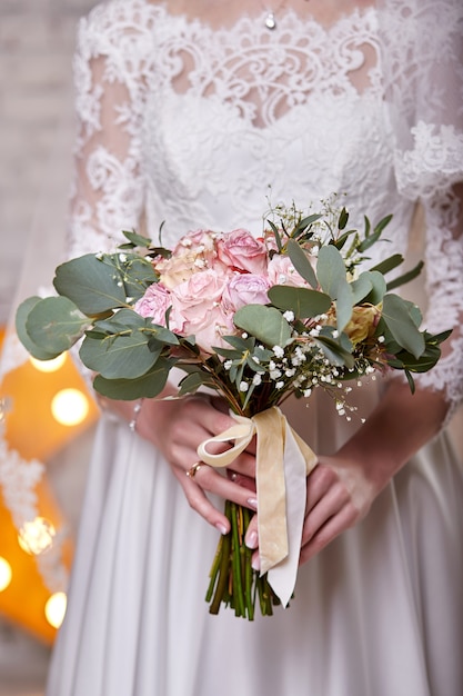 Bouquet in hands of the bride, woman getting ready before wedding ceremony