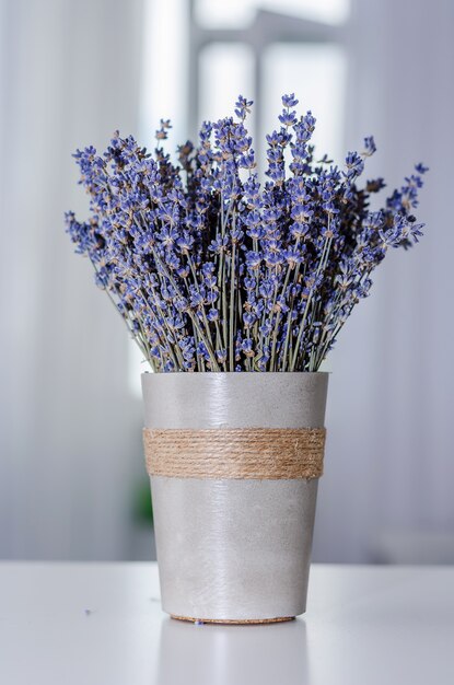 A bouquet of lavender in a gray glass on a table of gray interior.