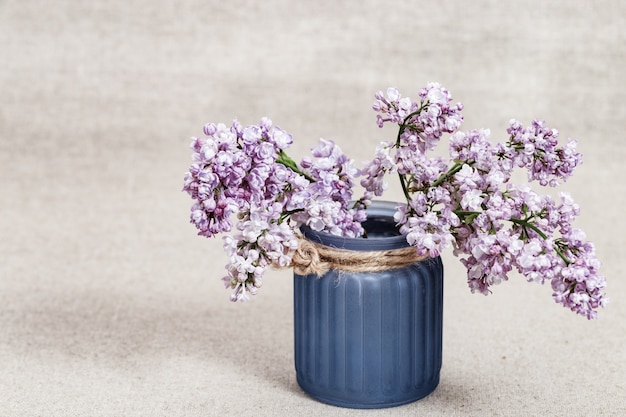 Bouquet of lilac flowers in blue glass vase on blurred