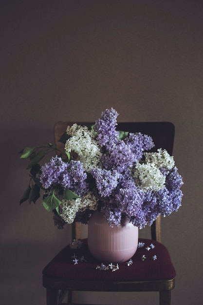 暗い背景の上に花瓶のライラックの花束