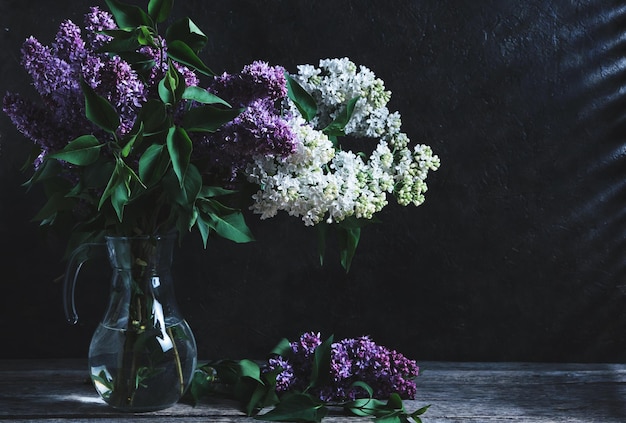 Bouquet of lilacs in jug at night in weak light of moon.