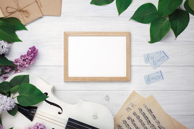 Photo a bouquet of lilacs with violin, chalk board and music sheet on a white wooden table. top wiev with space for your text