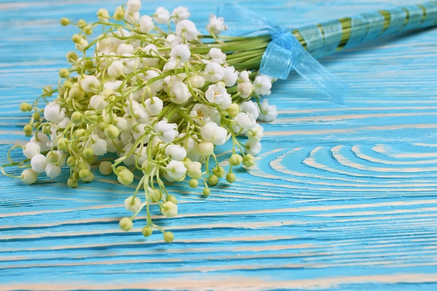 Bouquet of lilies of the valley on the blue wooden background with space for text