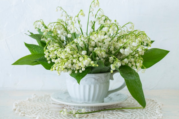 a bouquet of lilies of the valley in an old mug on the table 