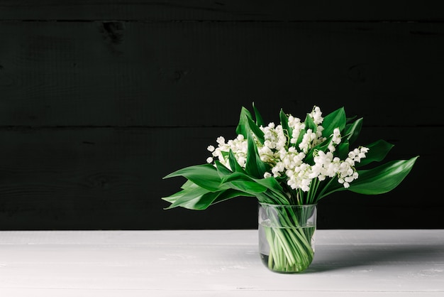 Bouquet of lilies of the valley on a white and black wooden background