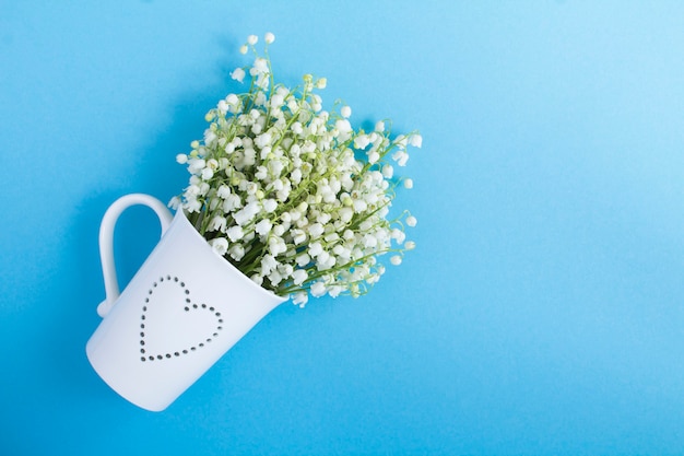 Bouquet of lilies of the valley in the white cup. Copy space. Top view.