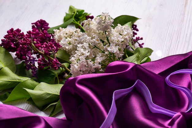 Bouquet of lillac flowers and purple drapery on white background. Copy space.