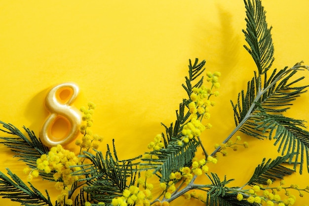 Foto un bouquet di mimosa e il numero 8 su sfondo giallo con copyspace è un biglietto di auguri per la giornata internazionale della donna l'8 marzo festa dell'indipendenza della donna festa di primavera primavera