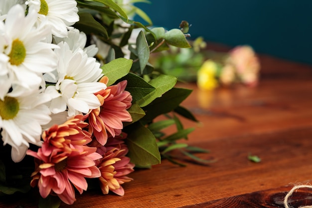 A bouquet of multi-colored chrysanthemums lies on a wooden table.