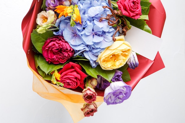 Bouquet of multi-colored roses with card on empty white background
