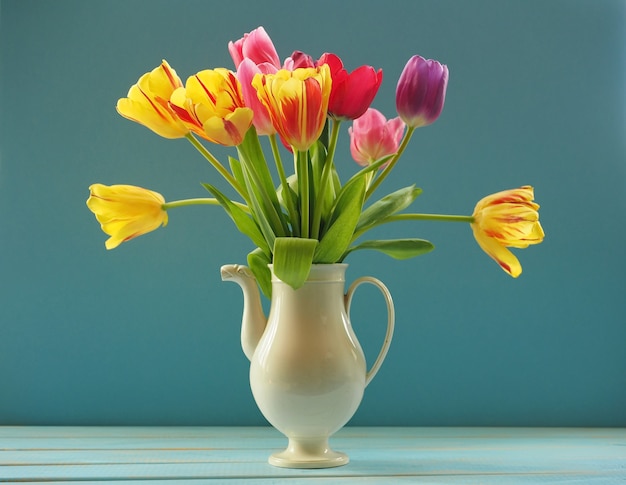 Bouquet of multicolored tulips in white ceramic tea pot