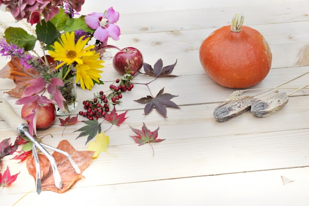 写真 木製のテーブルに紅葉の花の花束赤リンゴとカボチャ