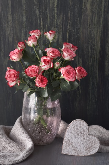 写真 グレーのウールスカーフと暗い素朴な木の木の心とピンクのバラの花束