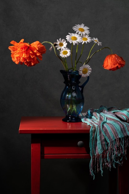 사진 테이블에 파란색 꽃병에 빨간 양귀비와 흰색 데이지의 꽃다발 회색 배경