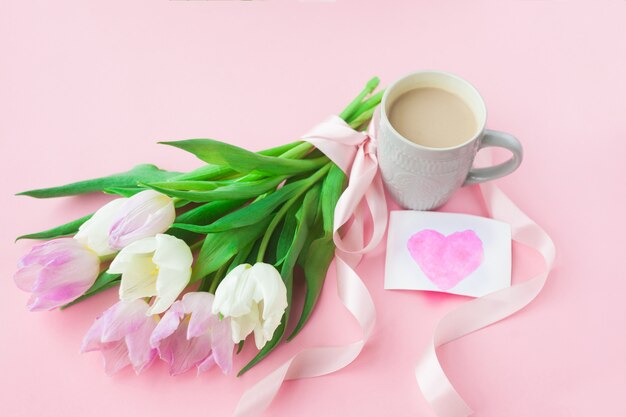 Фото Букет из тюльпанов и чашка кофе на розовом фоне пастельных.
