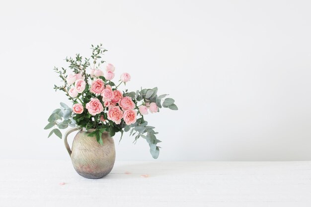 Bouquet of peony roses in ceramic jug on white background