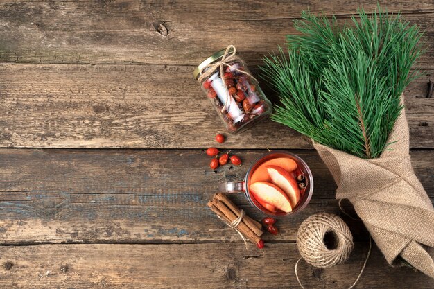 Bouquet of pine branches, mulled wine and cinnamon on a wooden background.