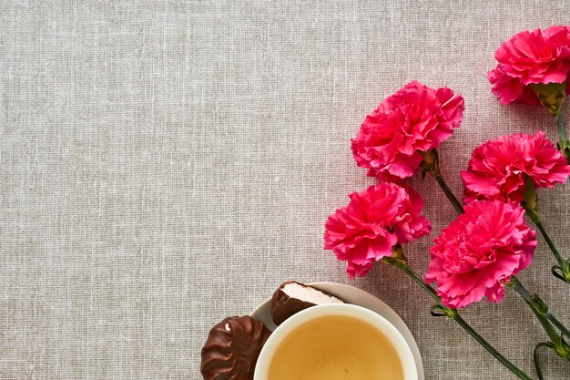 Bouquet of pink carnations with tea on gray fabric