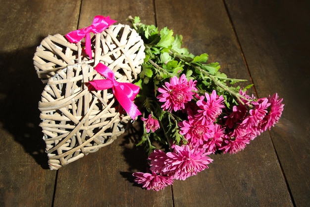 Bouquet of pink chrysanthemum and hearts on wooden table