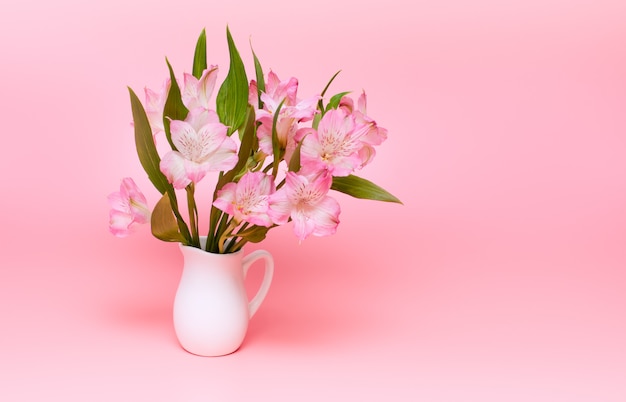 분홍색 배경에 분홍색 꽃의 꽃다발입니다. 흰색 꽃병에 봄 꽃입니다. 미니멀리즘.