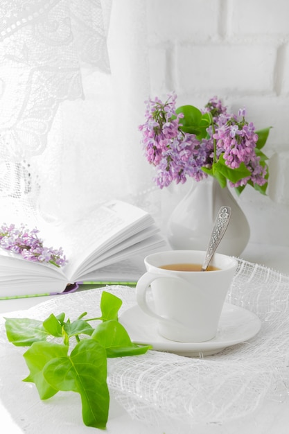 Bouquet of pink flowers (roses) and white service on a windowsill.