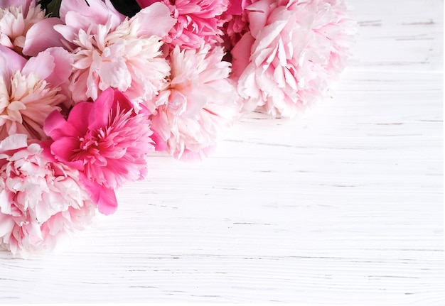 Bouquet of pink peonies on a white wooden background place for text