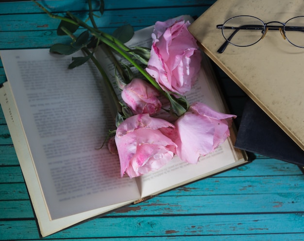 A bouquet of pink roses and books on rustic wood