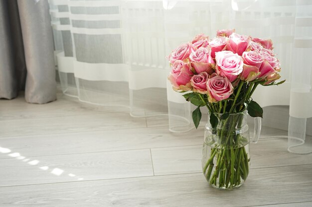 Photo bouquet of pink roses in a glass decanter with space for text beautiful bright floral background