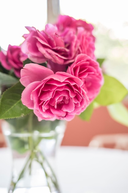 Photo bouquet of pink roses in a glass vase on table