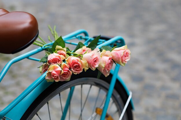 A bouquet of pink roses lies on the trunk of a beautiful women's bicycle