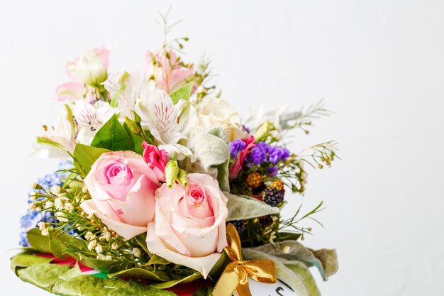 Bouquet of pink roses, lilies, green leaves on wooden blue table