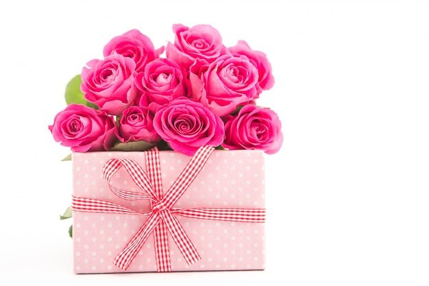 흰색 배경에 분홍색 선물 옆에 분홍색 장미 꽃다발