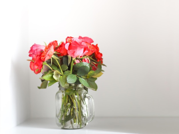 白い背景の上の透明な花瓶にピンクのバラの花束