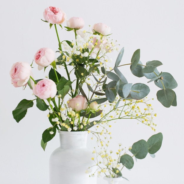白い背景の上の2つの白い花瓶にピンクのバラの花束