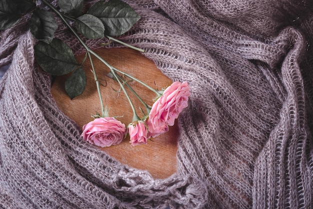 A bouquet of pink roses in a vase against the background of woollen fabric.