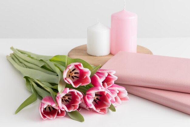 Bouquet of pink tulips books and candles on a white table