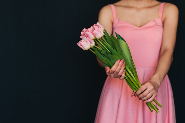 Bouquet of pink tulips in the hands of a girl in a dress