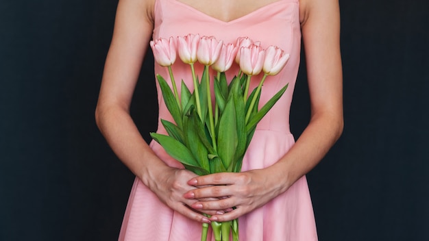 Bouquet of pink tulips in the hands of a woman