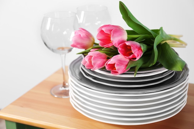 Bouquet of pink tulips over plates on wooden table