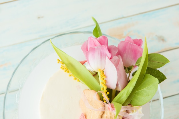 白のビスケットケーキにピンクのチューリップの花束