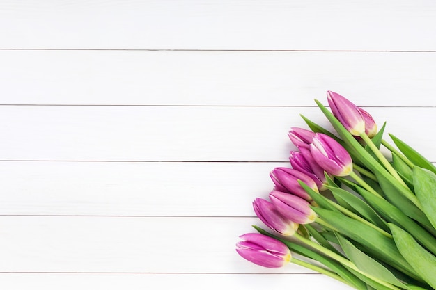 Bouquet of pink tulips on white wooden background. Top view, copy space