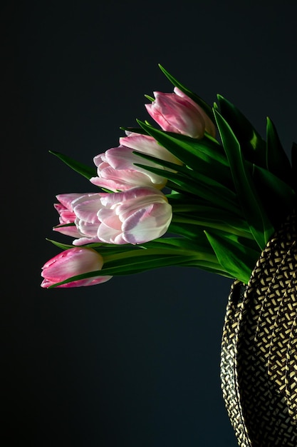 Photo bouquet of pink tulips in a wicker basket illuminated by the sun